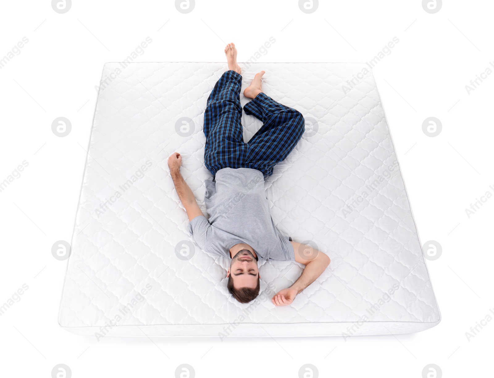 Photo of Young man sleeping on mattress against white background, above view