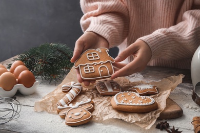 Woman holding delicious homemade Christmas cookie at wooden table, closeup