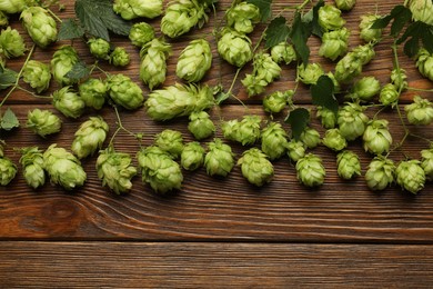 Photo of Branches of fresh green hops on wooden table, flat lay. Space for text