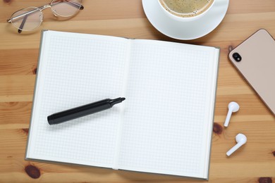 Photo of Empty notebook, coffee, smartphone and stationery on wooden table, flat lay
