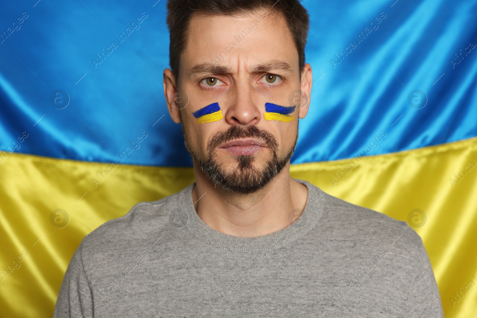 Photo of Angry man with face paint near Ukrainian flag