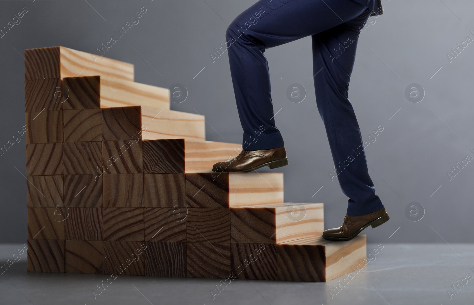 Image of Businessman walking up stairs against grey background, closeup. Career ladder concept