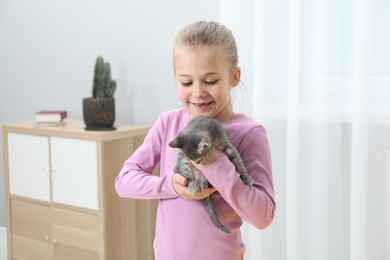 Photo of Little girl with cute fluffy kitten indoors
