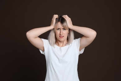Photo of Woman suffering from headache on dark brown background