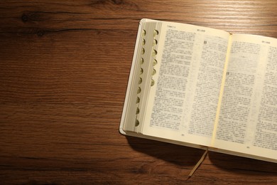 Photo of Open Bible on wooden table, top view. Space for text