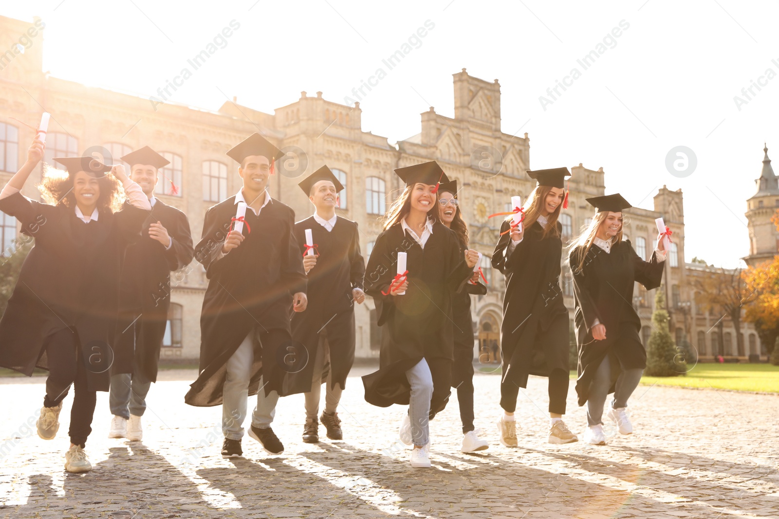 Photo of Happy students with diplomas outdoors. Graduation ceremony