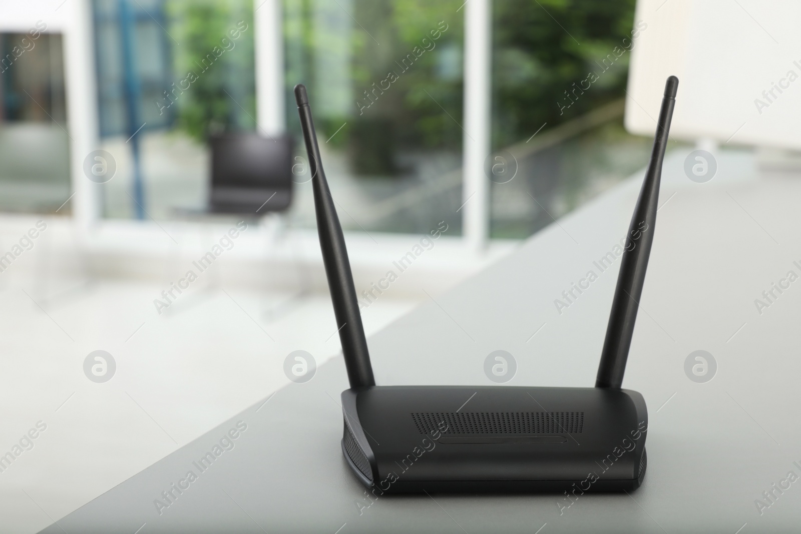 Photo of Modern Wi-Fi router on grey table indoors, space for text