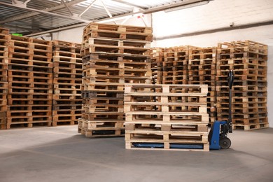 Modern manual forklift and wooden pallets in warehouse