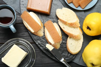 Photo of Tasty sandwiches with quince paste served on black wooden table, flat lay