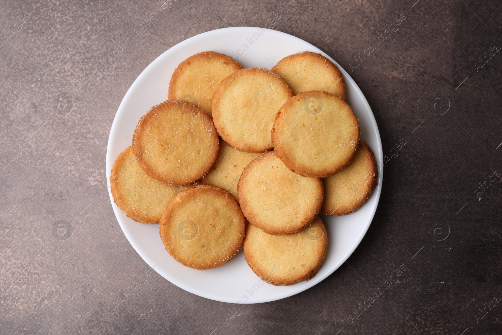 Photo of Tasty sweet sugar cookies on brown table, top view