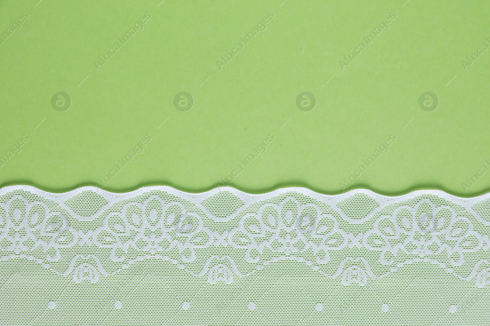 Photo of White lace on green background, top view. Space for text