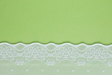 Photo of White lace on green background, top view. Space for text