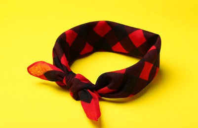 Photo of Tied red checkered bandana on yellow background