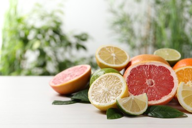 Different cut and whole citrus fruits on white wooden table. Space for text