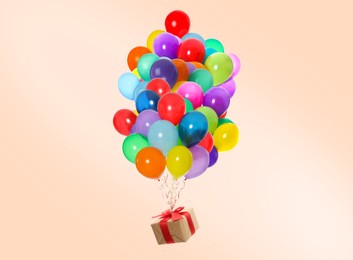 Many balloons tied to gift box on beige background