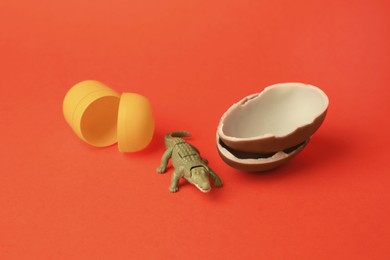 Photo of Slynchev Bryag, Bulgaria - May 25, 2023: Halves of Kinder Surprise Egg, plastic capsule and toy crocodile on orange background