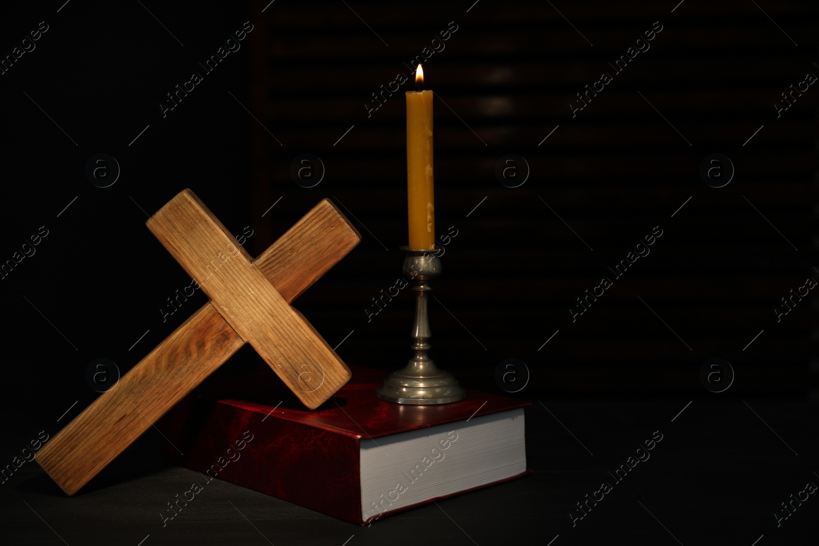 Photo of Church candle, Bible and wooden cross on table, space for text