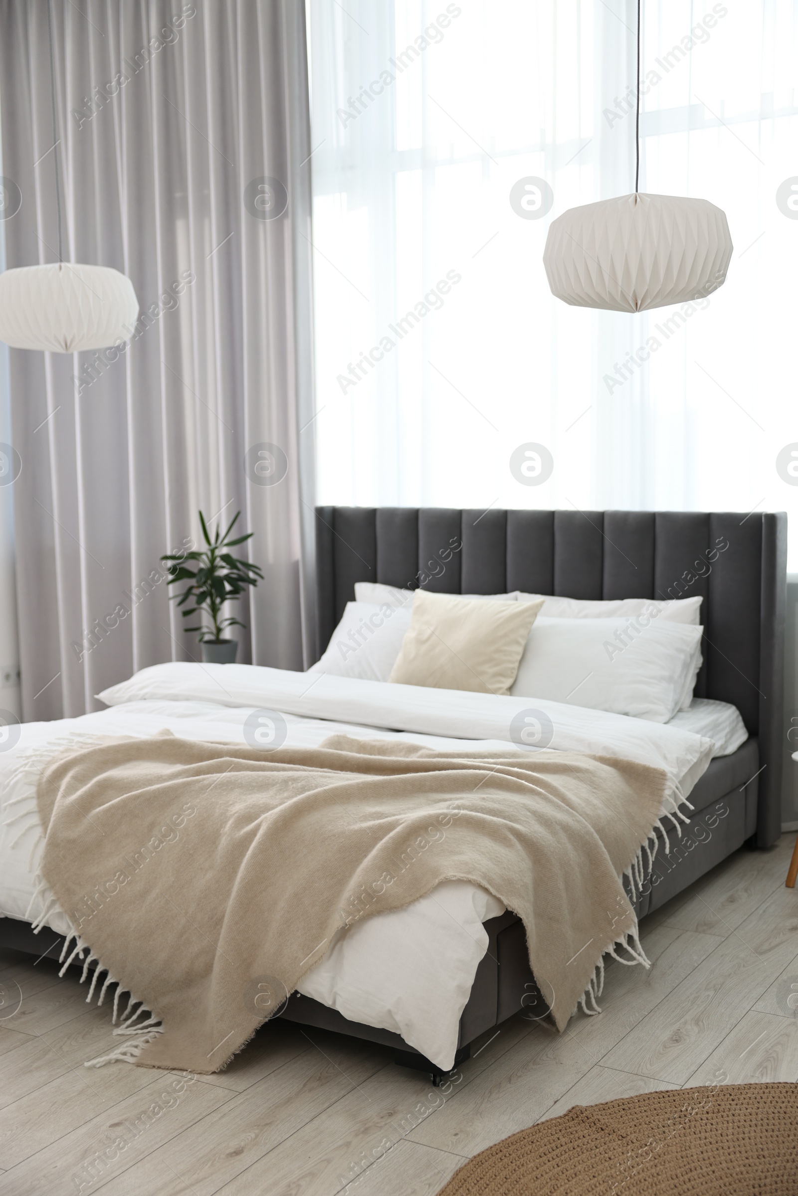 Photo of Soft beige plaid on bed in stylish bedroom. Interior design