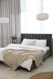 Photo of Soft beige plaid on bed in stylish bedroom. Interior design