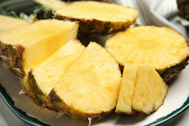 Photo of Plate with tasty cut pineapple on table, closeup