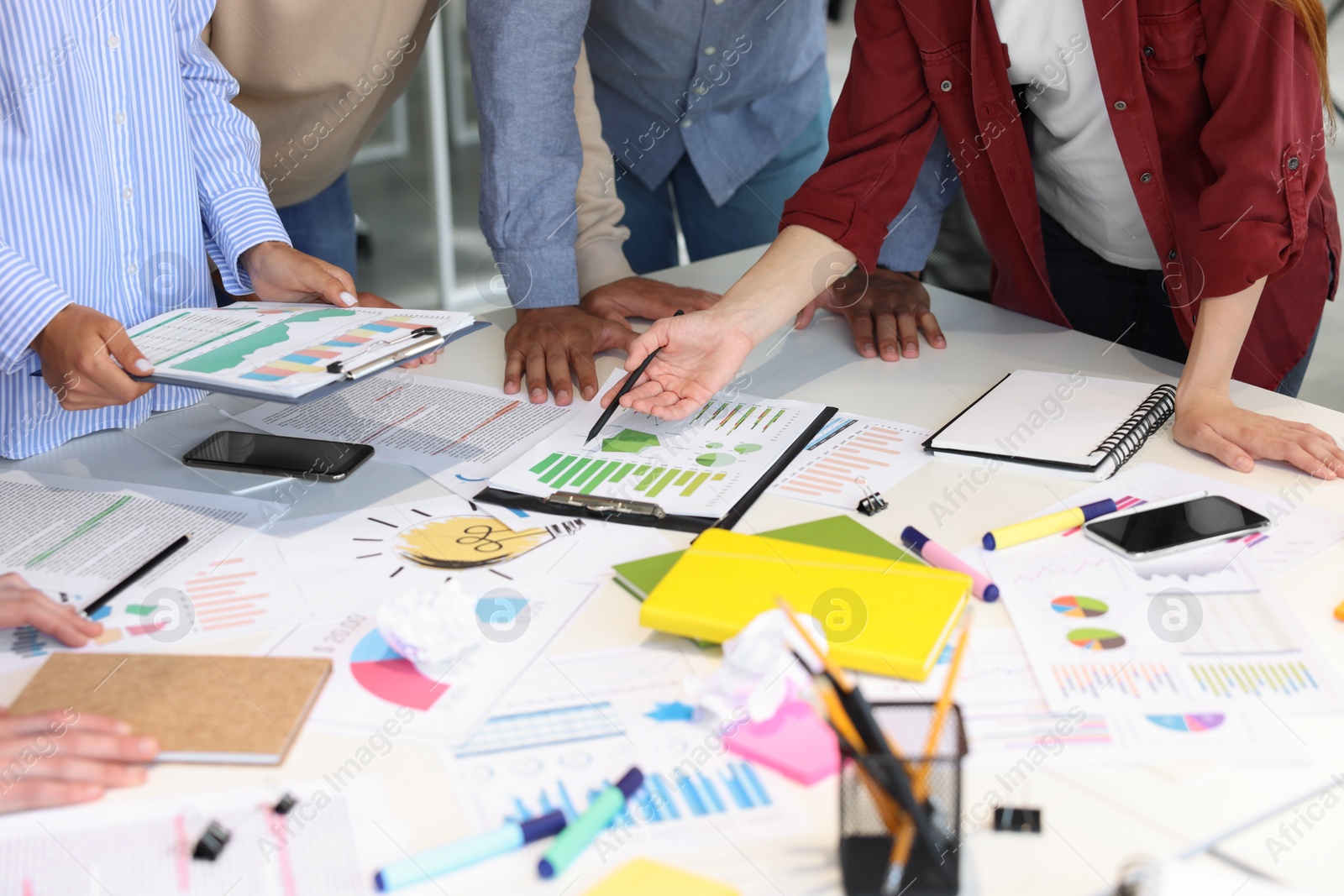 Photo of Team of employees working with charts at table, closeup. Startup project