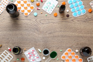 Photo of Flat lay composition with cough drops, syrup and pills on wooden background. Space for text