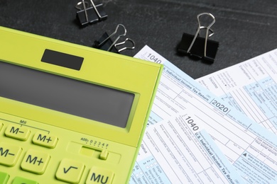 Photo of Calculator, documents and clips on black table, closeup. Tax accounting