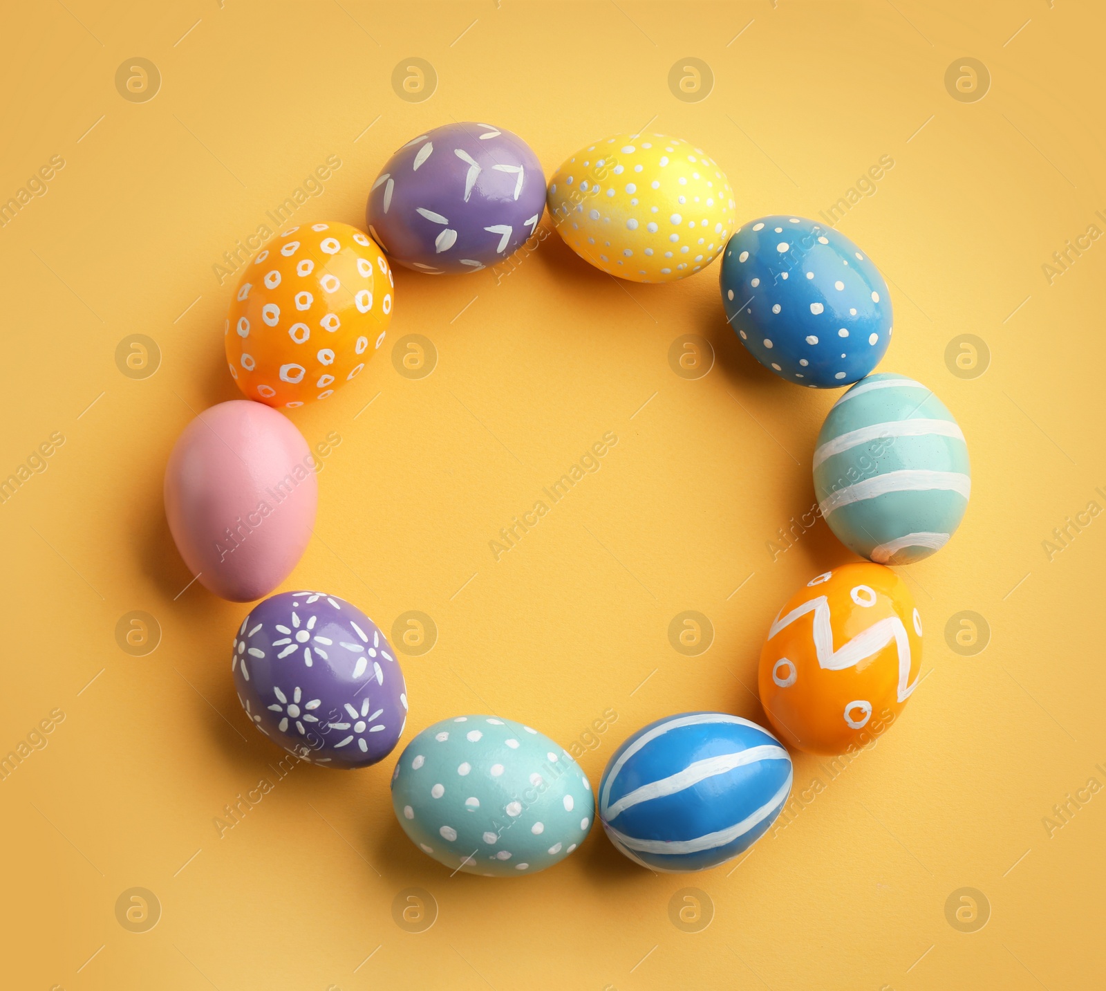 Photo of Frame made of painted Easter eggs on color background, top view. Space for text