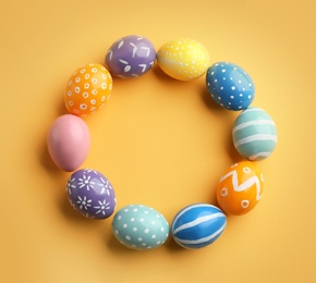 Frame made of painted Easter eggs on color background, top view. Space for text