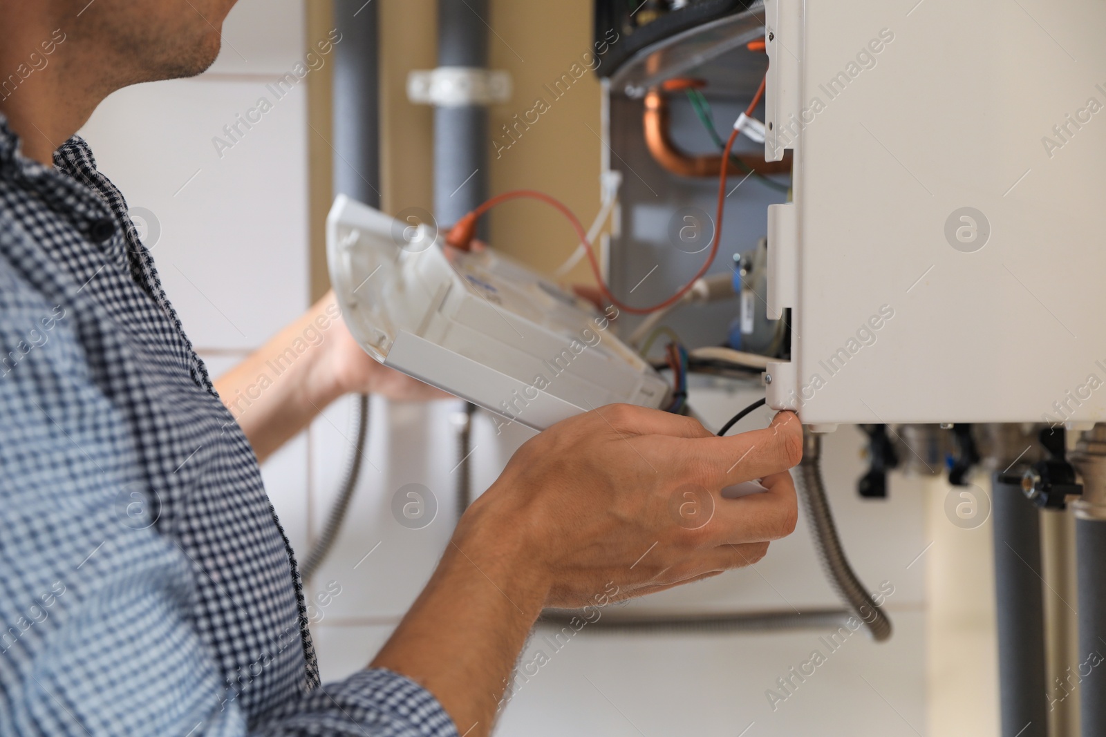 Photo of Man opening top of gas boiler indoors, closeup