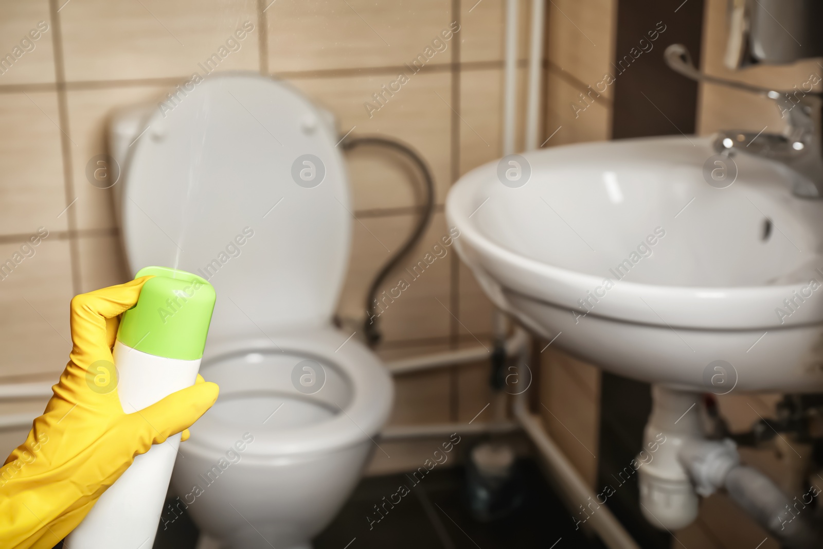 Photo of Person spraying air freshener in bathroom
