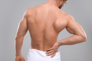 Photo of Man suffering from back pain on grey background, back view