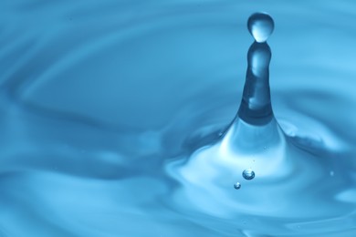 Photo of Drops falling into clear water, closeup. Space for text