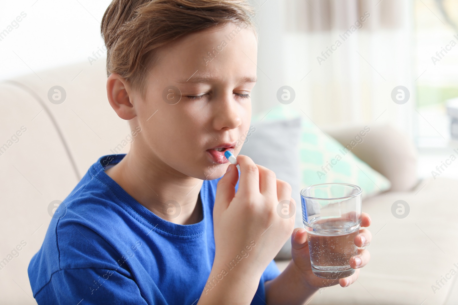 Photo of Little child taking pill at home. Danger of medicament intoxication