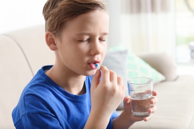 Photo of Little child taking pill at home. Danger of medicament intoxication