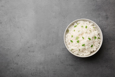 Bowl of boiled rice on color background, top view with space for text