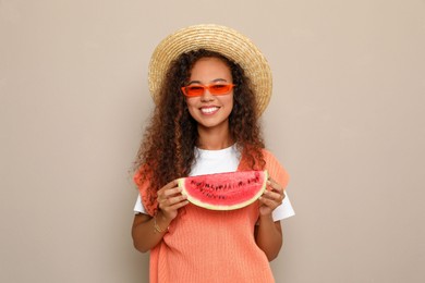 Photo of Beautiful young African American woman with slice of watermelon on beige background