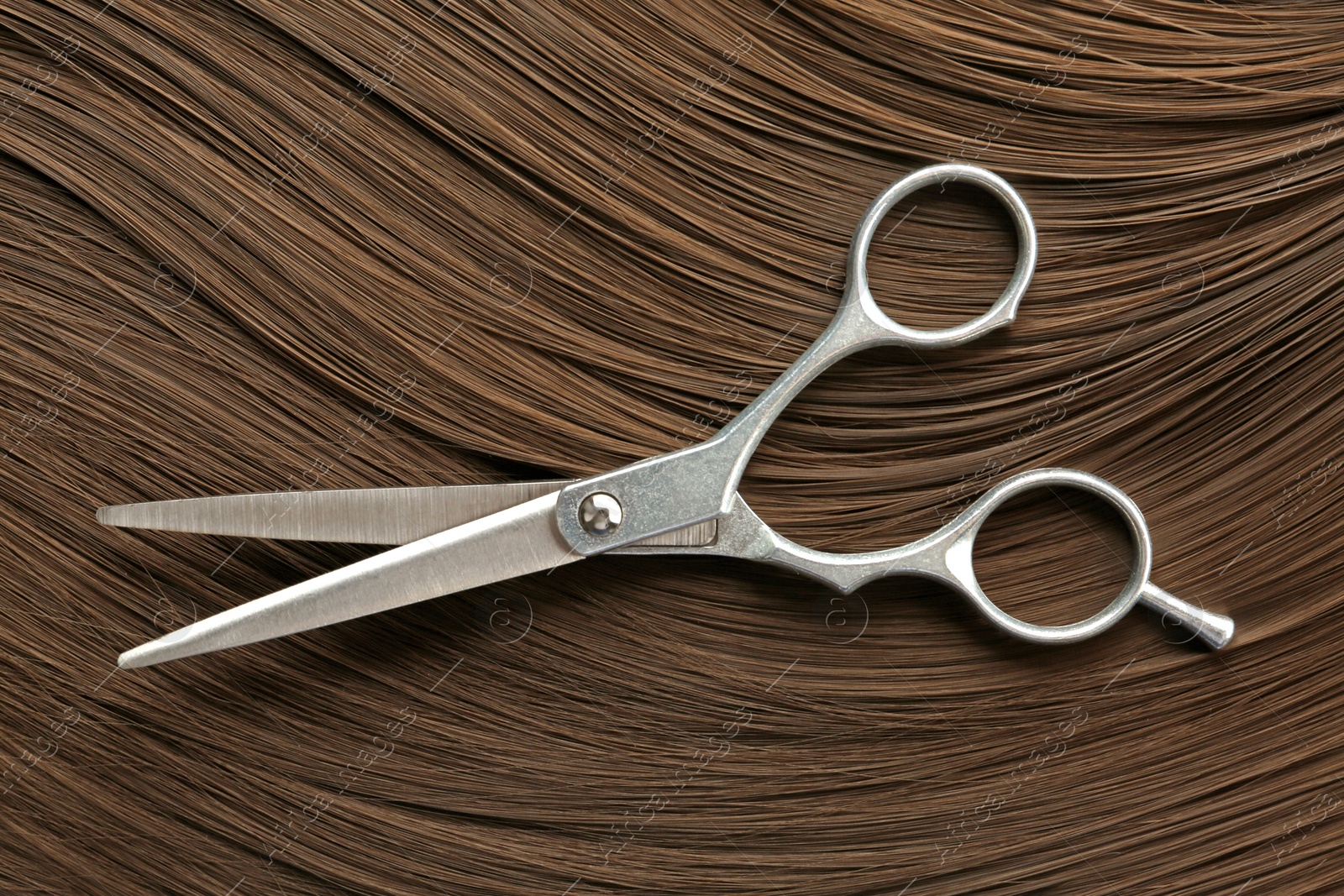 Photo of Scissors on brown hair, top view. Hairdresser service