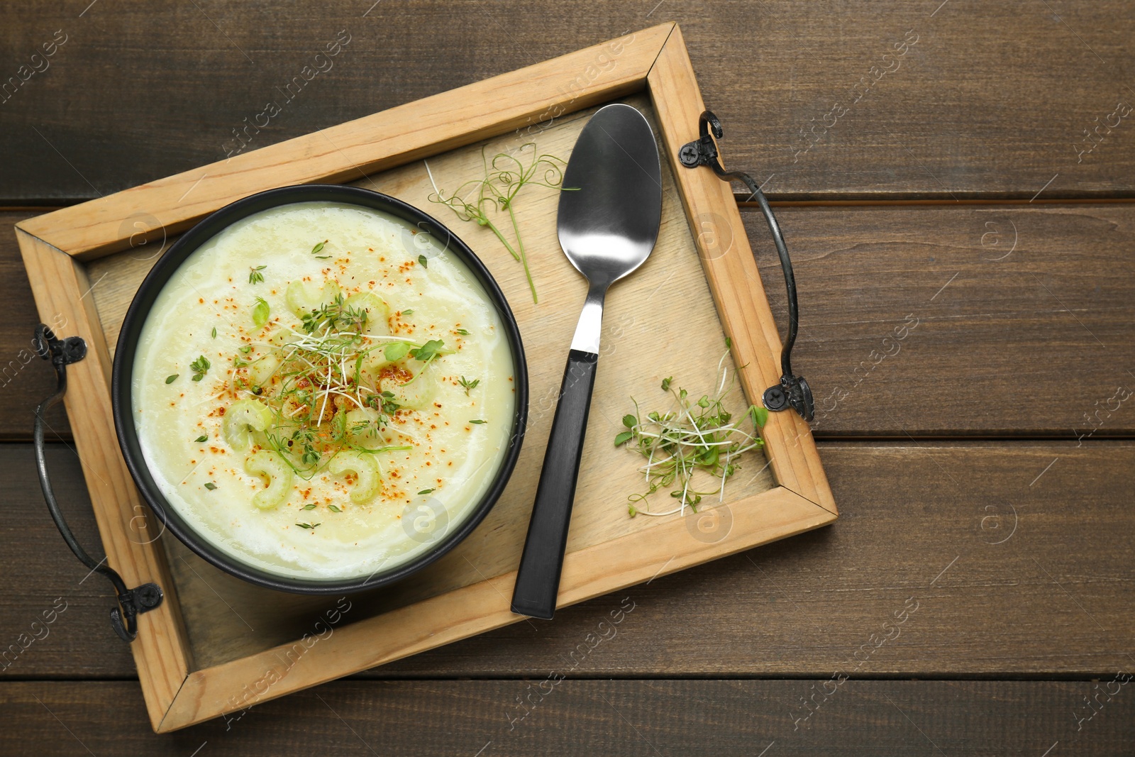 Photo of Bowl of delicious celery soup served on wooden table, top view. Space for text