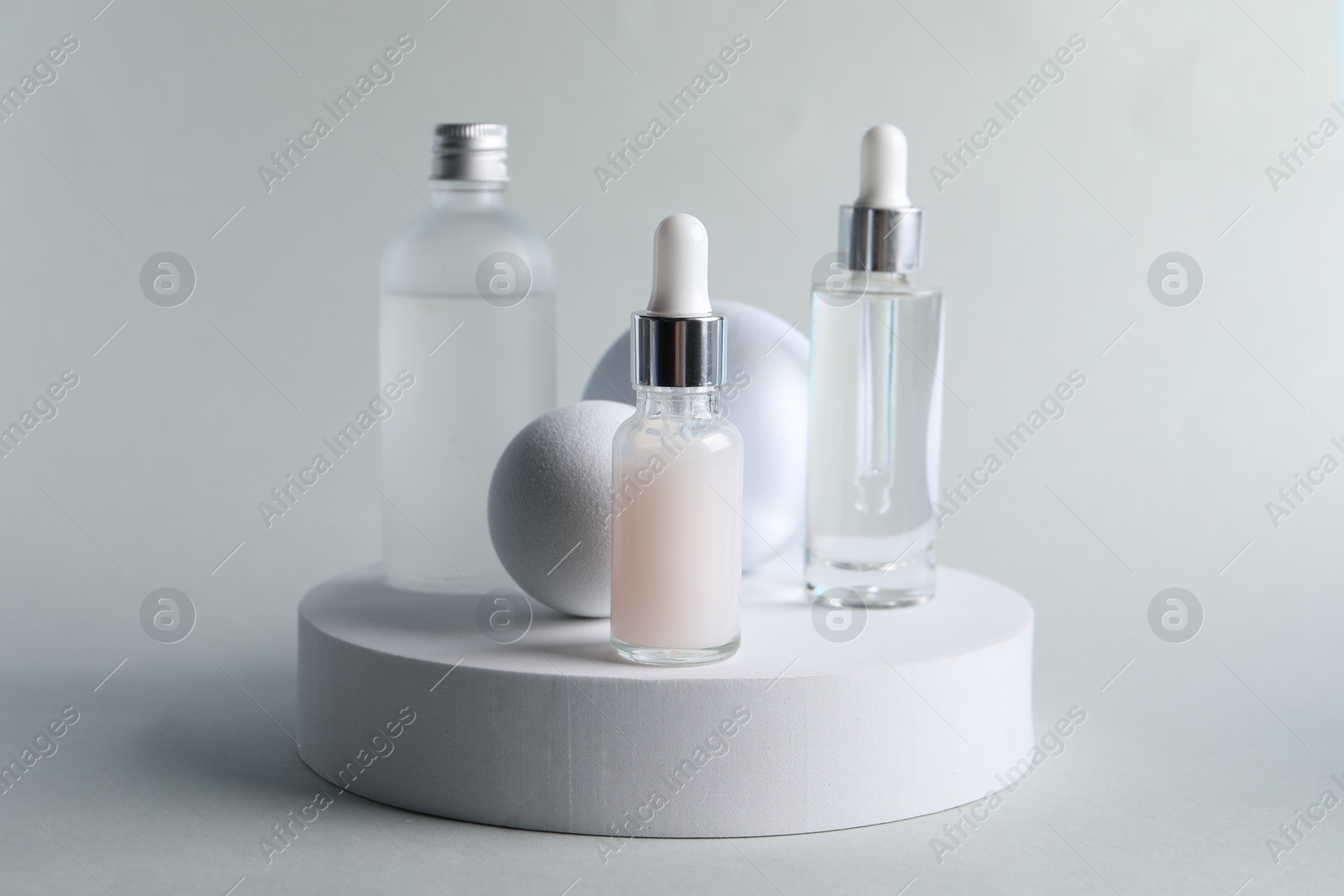 Photo of Stylish presentation of bottles with cosmetic serums on light grey background