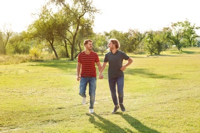 Photo of Happy gay couple running in countryside on sunny day
