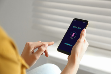 Woman using voice search on smartphone indoors, closeup