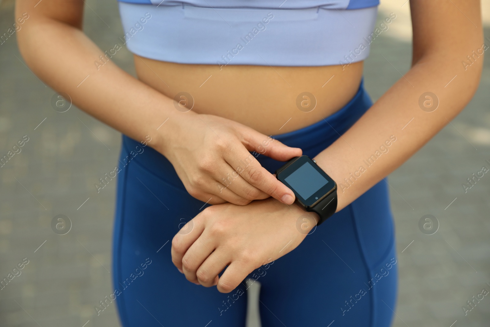 Photo of Woman using stylish smart watch during training outdoors, closeup