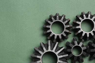 Photo of Different stainless steel gears on light green background, flat lay. Space for text