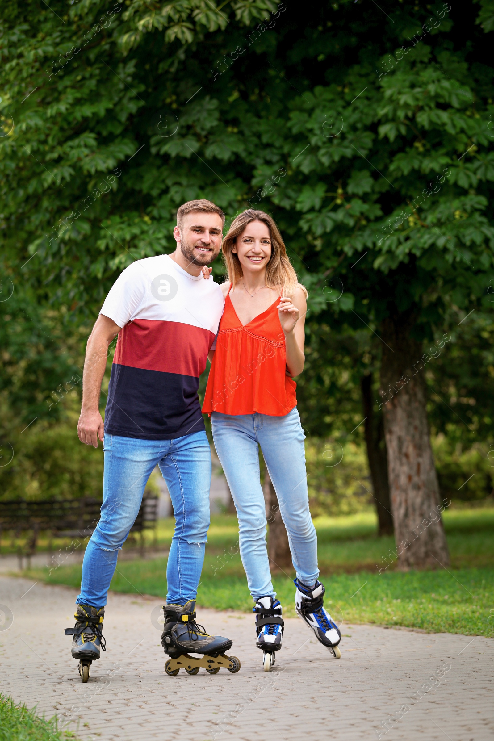 Photo of Young happy couple roller skating in summer park