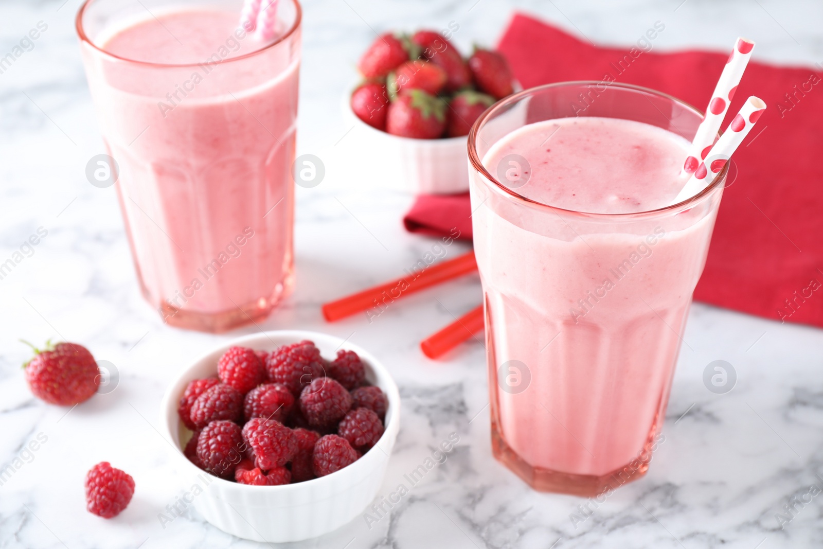 Photo of Tasty milk shakes and berries on white marble table