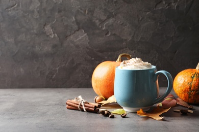 Photo of Cup with pumpkin spice latte on gray table. Space for text
