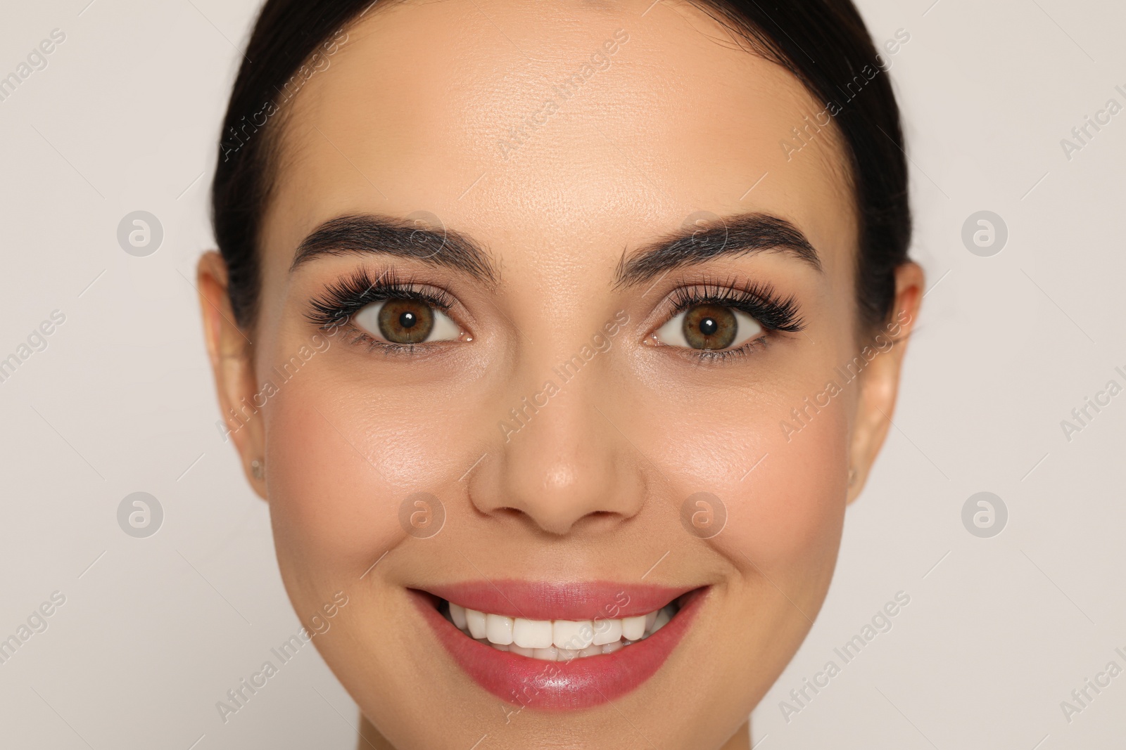 Photo of Beautiful young woman with long eyelashes on light background, closeup