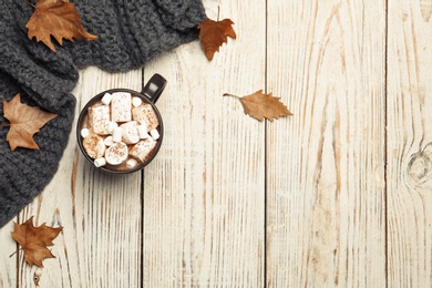 Flat lay composition with hot cozy drink and autumn leaves on wooden background. Space for text