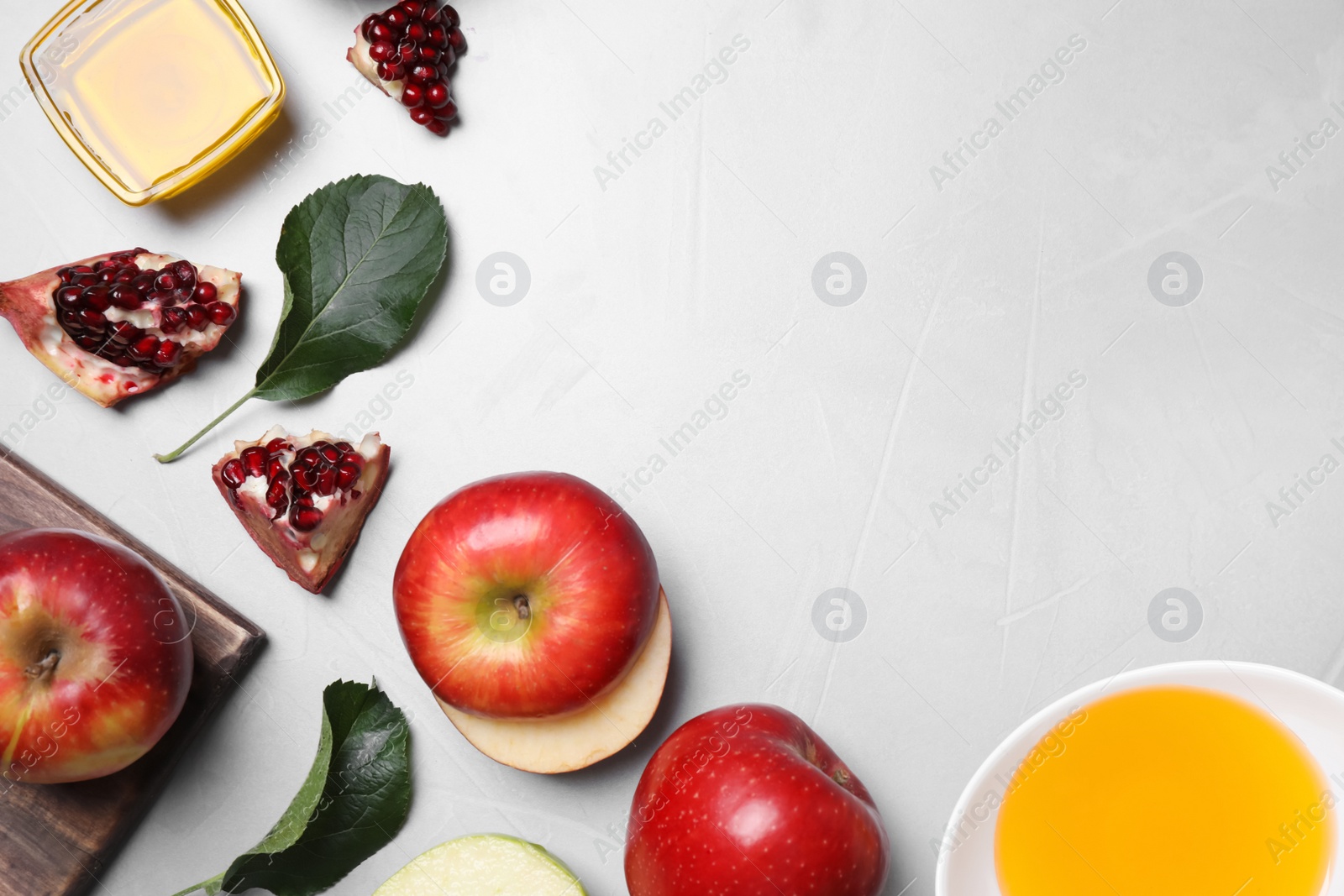 Photo of Honey, apples and pomegranate on light table, flat lay with space for text. Rosh Hashanah holiday